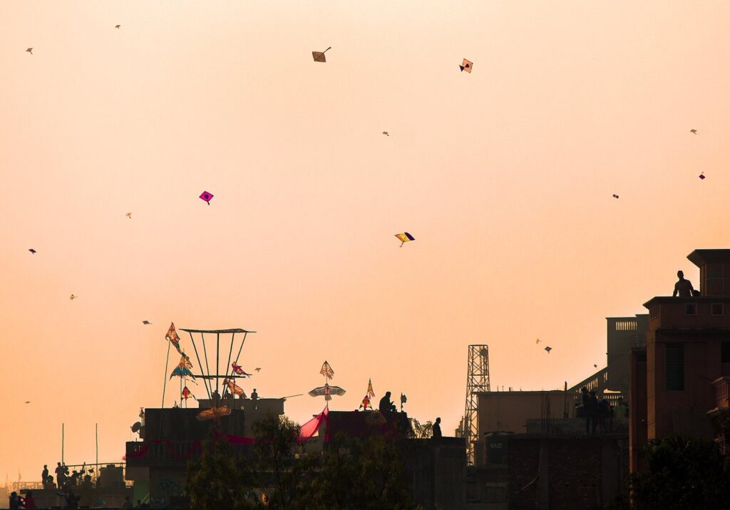 Under the expanse of the Shakrain festival sky, vibrant kites soar in a mesmerizing dance, while people below engage in the joyous tradition of kite-f