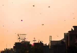 Under the expanse of the Shakrain festival sky, vibrant kites soar in a mesmerizing dance, while people below engage in the joyous tradition of kite-f